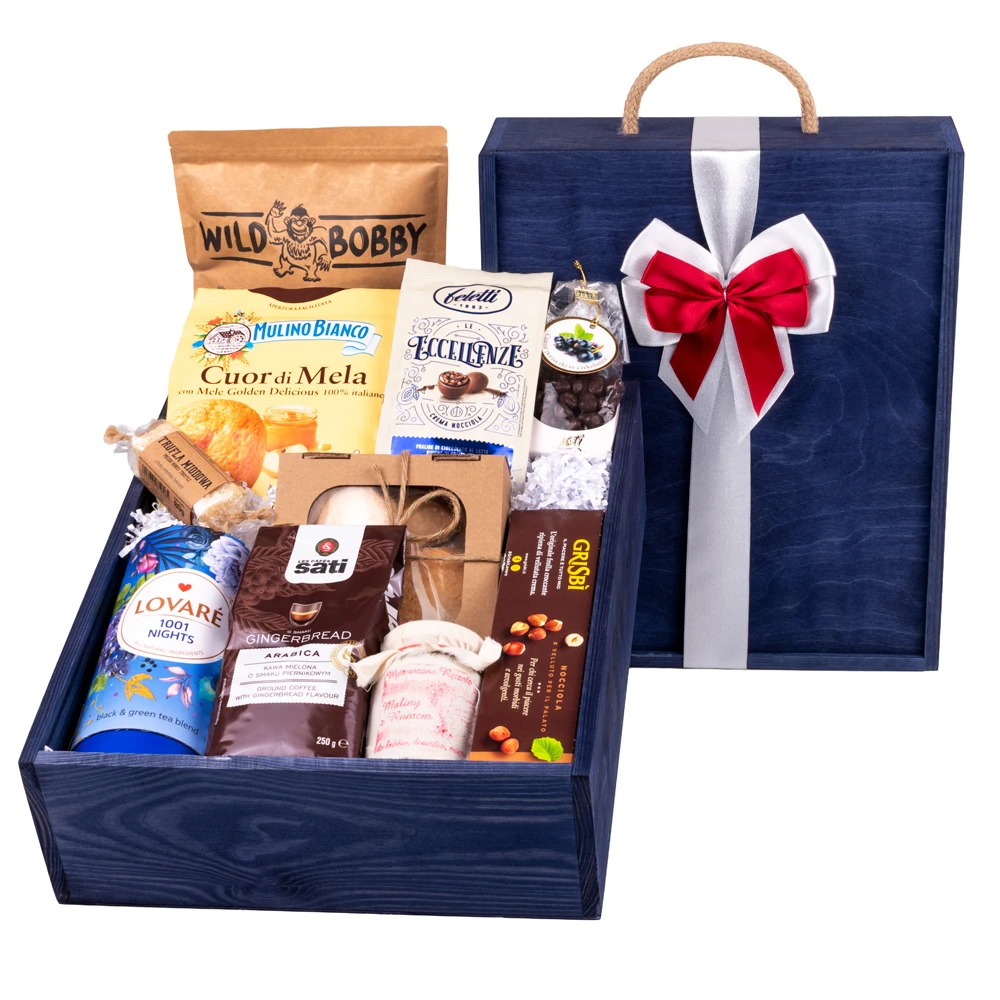 Ekskluzywna, bejcowana na granatowo drewniana skrzynia prezentowa z grawerem i okazałą, dwukolorową biało-czerwoną kokardą. Wewnątrz bogaty zestaw delikatesów: kawa Sati Gingerbread, herbata Lovare 1001 Nights w tubie, ciastka Mulino Bianco, praliny Feletti, Grisbì, chipsy z bobu Wild Bobby oraz konfitura malinowa, ułożone na białych wiórkach dekoracyjnych.