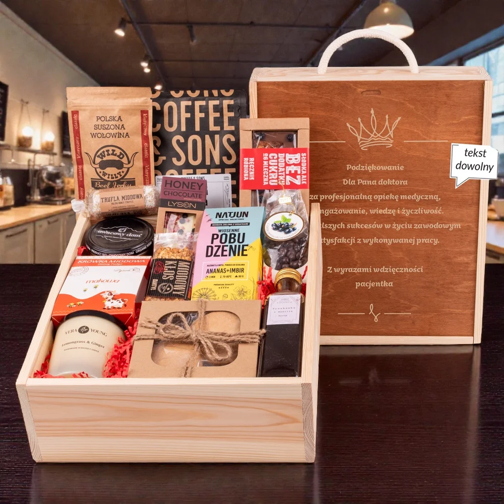 Personalizowana drewniana skrzynka prezentowa z grawerem „Podziękowanie dla Pana Doktora” i ciemnym wieczkiem. Wewnątrz bogaty zestaw polskich specjałów: kawa Coffee & Sons, suszona wołowina Wild Willy, herbata Natjun „Wiosenne Pobudzenie”, miody rzemieślnicze, czekolada bez cukru oraz świeca zapachowa Vera Young na czerwonym wypełnieniu.